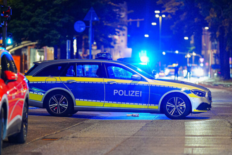 Auf einer nächtlichen Straße in Hamburg steht ein Polizeiauto – zuvor hatten Unbekannte Fußballfans angegriffen