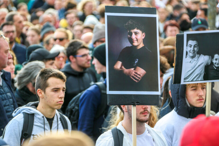 In weiß gekleidete Jugendliche halten ein Schild mit dem Bild des in Crépol ermordeten Thomas Perotto hoch