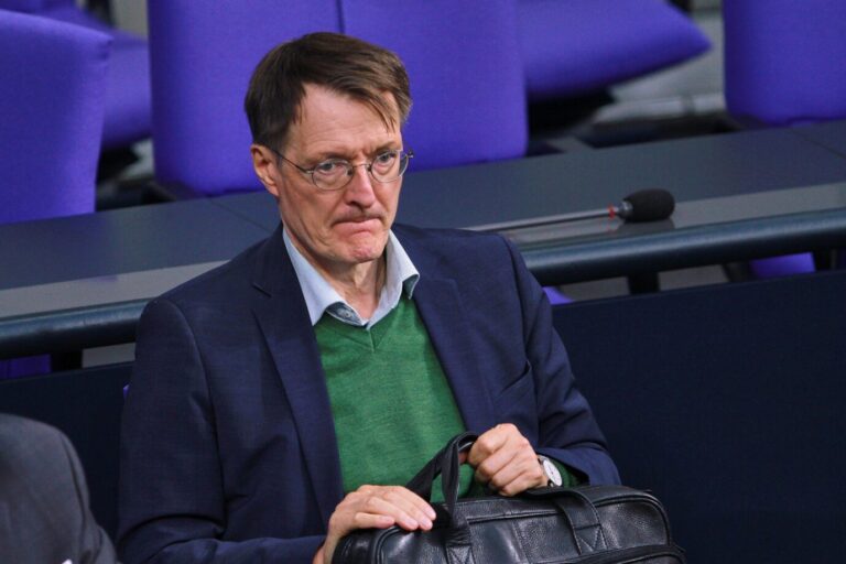 Der SPD-Bundestagsabgeordnete Karl Lauterbach (SPD) schaut verkniffen und presst seine Hände um eine Herrentasche