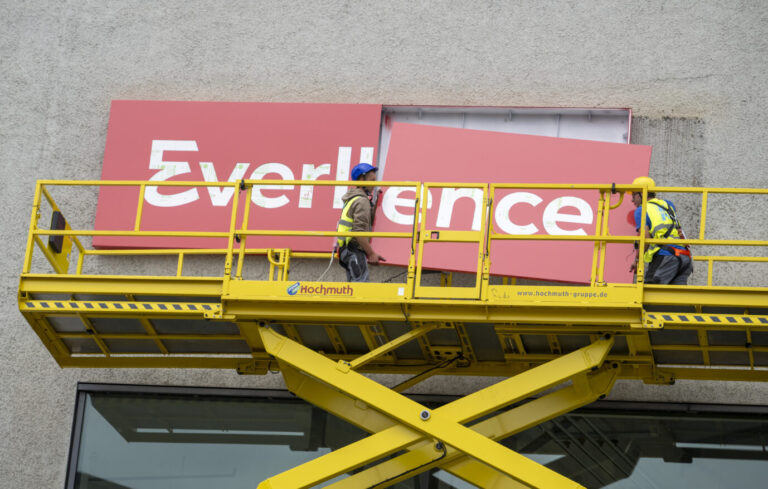 Zwei Arbeiter montieren von einer Hebebühne aus den Schriftzug „Everllence" an einer Fassade. Der Motorenhersteller MAN Energy Solutions SE tritt künftig unter dem neuen Namen am Markt auf. VW musste die meisten seiner Anteile an dem Unternehmen verkaufen. Diesel ist immer noch gefragt, aber auch Wasserstoff steht hoch im Kurs.