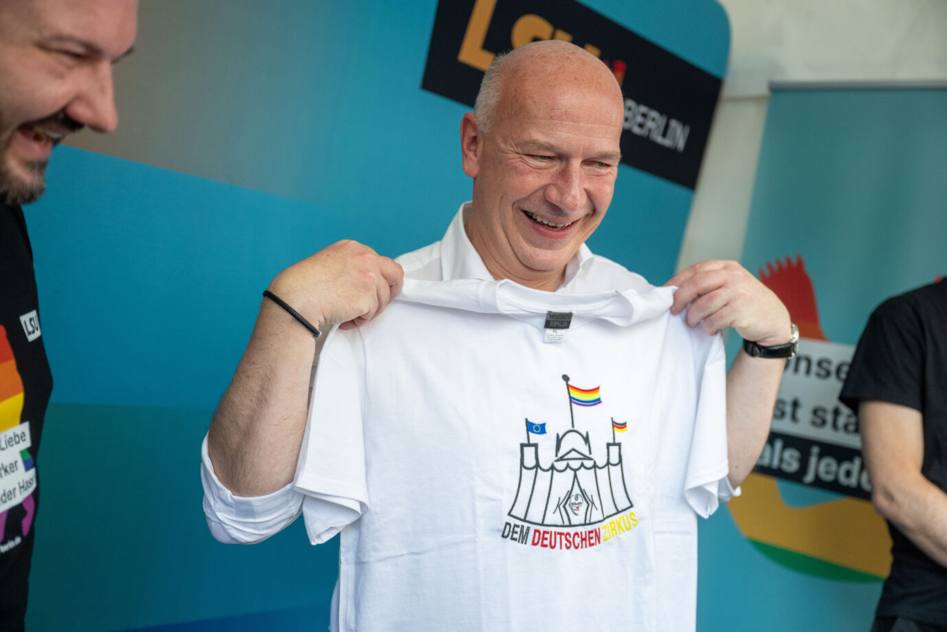 Der Regierende Bürgermeister Berlins, Kai Wegner (CDU), lacht albern und sieht sehr wenig bürgerlich aus, er hält ein T-Shirt in den Händen