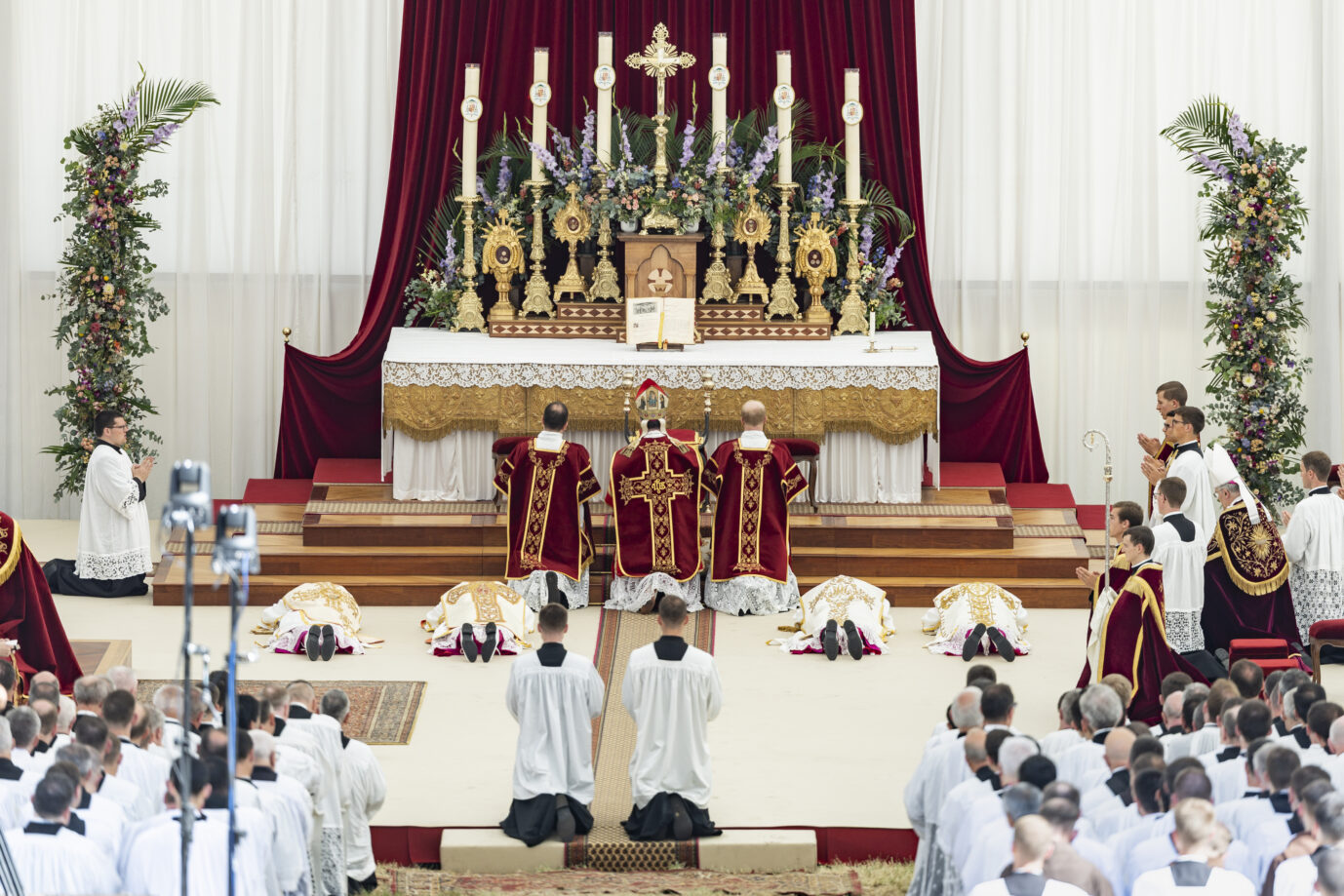 In einem weißen Kirchenraum knien katholische Anhänger der Pius-Bruderschaft nieder