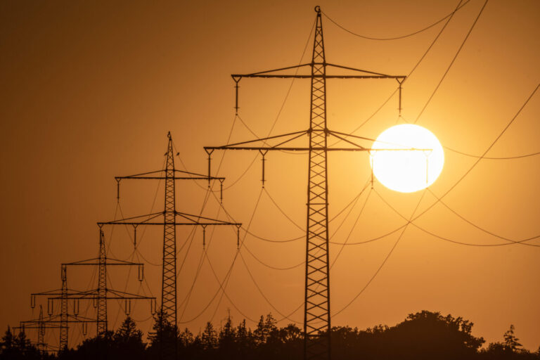 Eine helle Sonne scheint über schemenhaft erkennbaren Strommasten