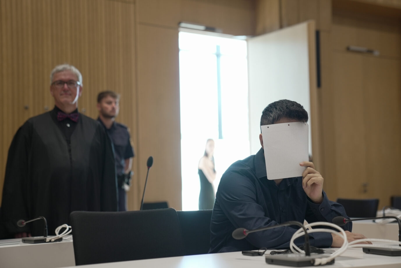 Der IS-Anhänger, Vergewaltiger, Jesidenversklaver und Angeklagte Twana H. hält sich im Gerichtssaal ein Blatt Papier vor das Gesicht