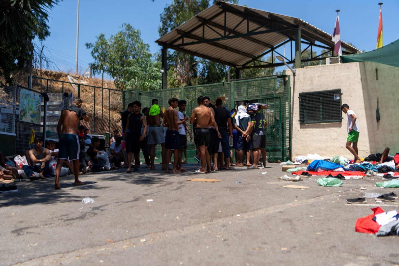 Vor einem kleinen grauen Steinhaus stehen Migranten – eine Szene aus der spanischen Enklave Ceuta