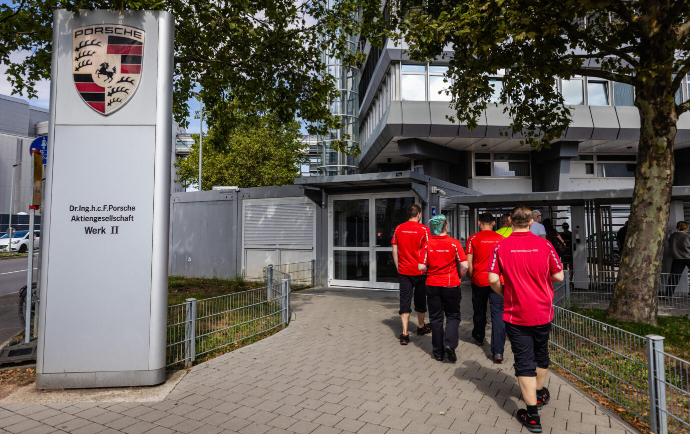 Mitarbeiter von Porsche gehen zu einem Gebäude am Firmensitz in Stuttgart-Zuffenhausen. Mitarbeiter von Porsche gehen zu einem Gebäude am Firmensitz in Stuttgart-Zuffenhausen: Das Paket wurde mit der IG Metall und dem Arbeitgeberverband Südwestmetall verhandelt. Foto: picture alliance/dpa | Christoph Schmidt