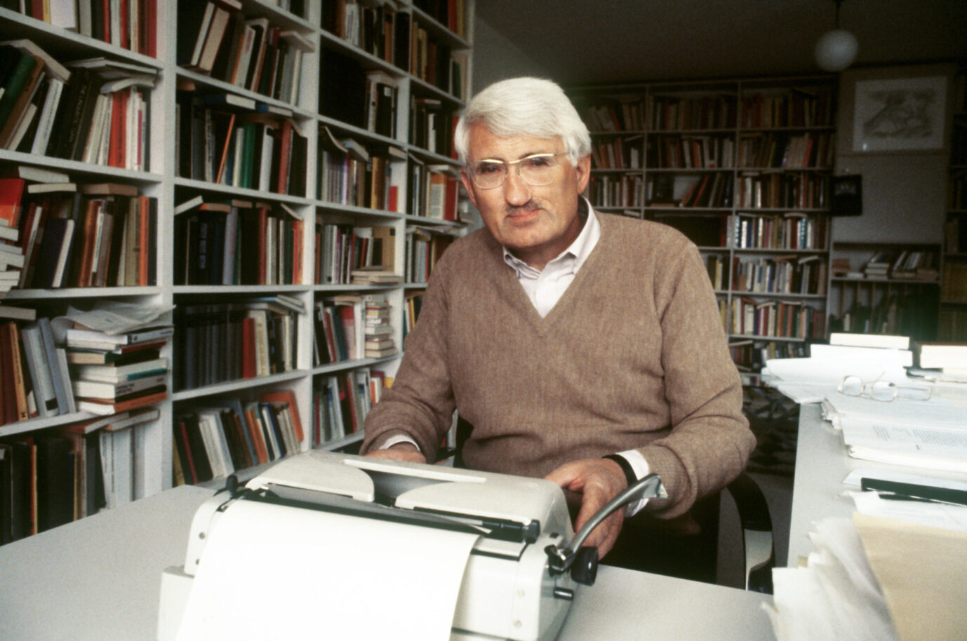 Jürgen Habermas sitzt an einem Schreibtisch hinter einer Schreibmaschine.