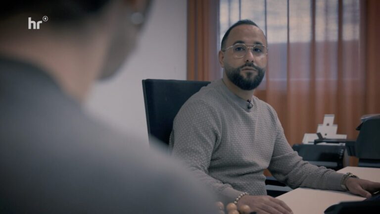 Der Sachbearbeiter der Ausländerbehörde Darmstadt, Herr Abduljabber: Insgesamt entscheiden 27 Mitarbeiter in der Behörde über Aufenthaltstitel. Foto: Screenshot HR / JF