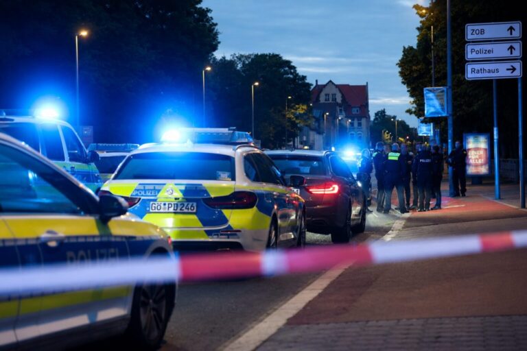 Polizisten und Polizeifahrzeuge stehen hinter einer Absperrung. Ein Polizist ist bei einer Auseinandersetzung zwischen zwei Personengruppen im niedersächsischen Göttingen angeschossen worden. Foto: picture alliance/dpa | Stefan Rampfel