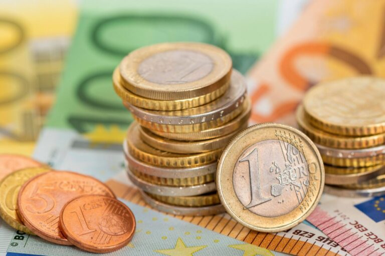 Eurowährung und Geldscheine Viele Euro Banknoten und Münzen liegen auf einem Haufen zusammen als Symbolbild für eine starke Eurowährung in Europa. Pro-Kopf-Verschuldung auf Rekordhoch.