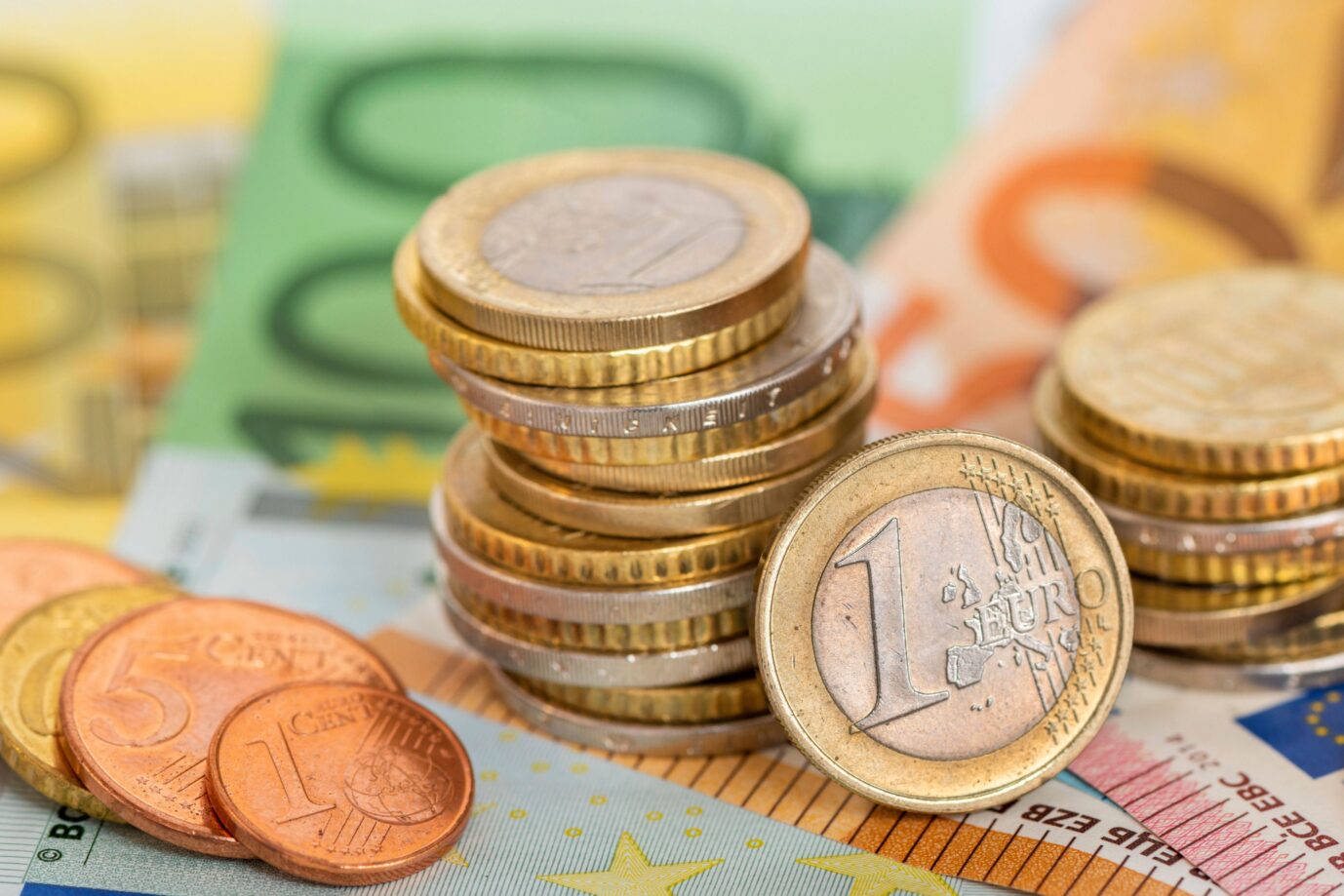 Eurowährung und Geldscheine Viele Euro Banknoten und Münzen liegen auf einem Haufen zusammen als Symbolbild für eine starke Eurowährung in Europa. Pro-Kopf-Verschuldung auf Rekordhoch.