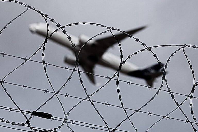 Das Bild zeigt ein abhebendes Flugzeug hinter einem Stacheldrahtzaun. Es ist ein Symbolbild für einen journalistischen Text über die Migrationswende der Bundesregierung.
