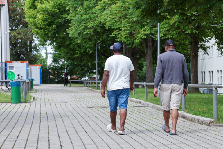 Zwei Bewohner gehen in der Zentralen Aufnahmeeinrichtung für Asylbewerber in Bayern über das Gelände. Die Innenministerkonferenz (IMK), die am 11.06.2025 beginnt, wird sich unter anderem mit der Migrationspolitik befassen.