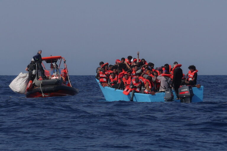 Migranten an Bord eines überfüllten Bootes reagieren, als sie während einer Rettungsaktion in der Such- und Rettungszone (SAR) im zentralen Mittelmeer vor der Küste Libyens am 11. August 2025 von der Besatzung des von der deutschen Nichtregierungsorganisation Sea-Watch betriebenen Such- und Rettungsschiffs „Sea-Watch 5“ angefahren werden. Das Such- und Rettungsschiffs „Sea-Watch 5“ fährt auf ein Boot voll Migranten zu (Symbolbild): Italiens Vize-Ministerpräsident Salvini will, dass Deutschland seine Schlepper-NGOs „zurückpfeift“. Foto: picture alliance / REUTERS | Louisa Gouliamaki