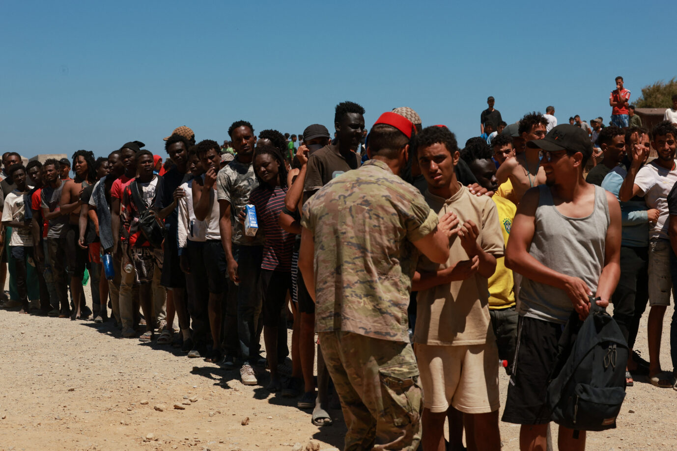 Am Sonntag, nachdem angeblich alle abgereist sind, verteilen Soldaten am Strand von Ceuta Wasser an die Migranten.