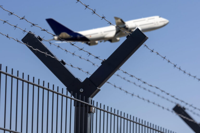 (Fotomontage) Startendes Flugzeug hinter einem Maschendrahtzaun. Es ist ein Symbolbild für Abschiebungen nach Afghanistan. Teile der SPD kritisieren diese Praxis.