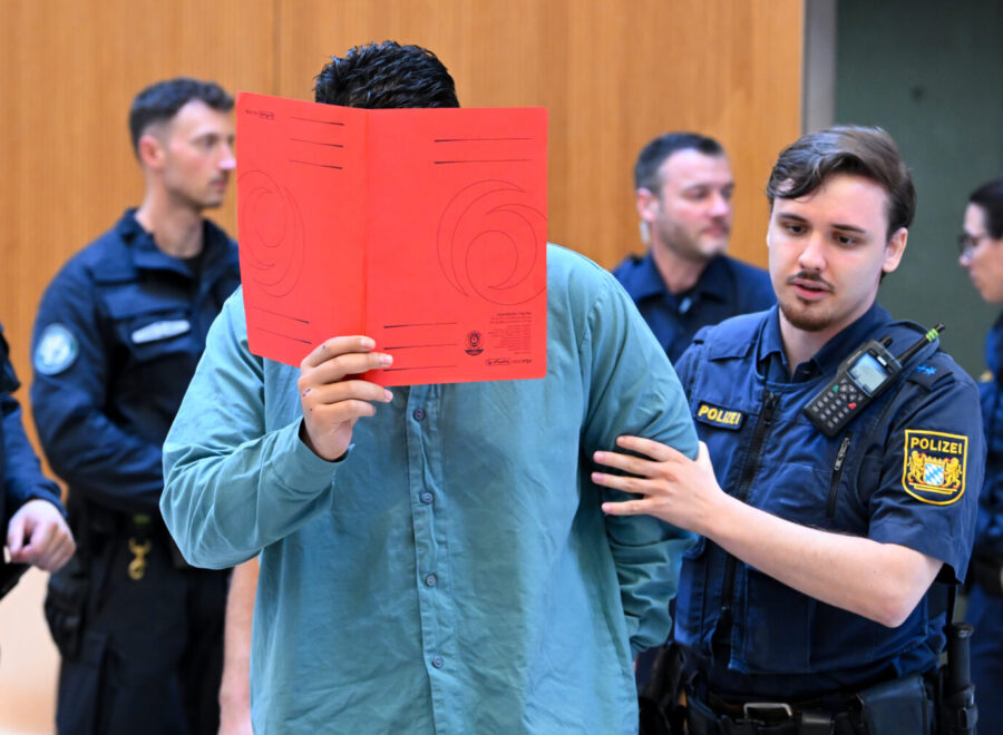 Der Angeklagte Farhad N. wird zu Prozessbeginn von Polizeibeamten in den Prozesssaal geführt. Farhad N.: Das Oberlandesgericht München stellte es eine besondere Schwere der Schuld fest. Foto: picture alliance/dpa | Sven Hoppe. In Verdi-Demo gerast