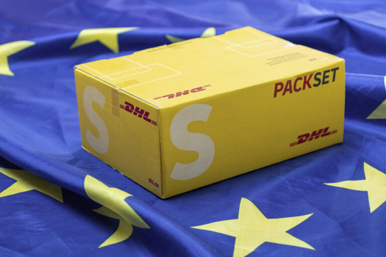Symbolbild Verpackungsverordnung: DHL-Päckchen auf einer Flagge der Europäischen Union
