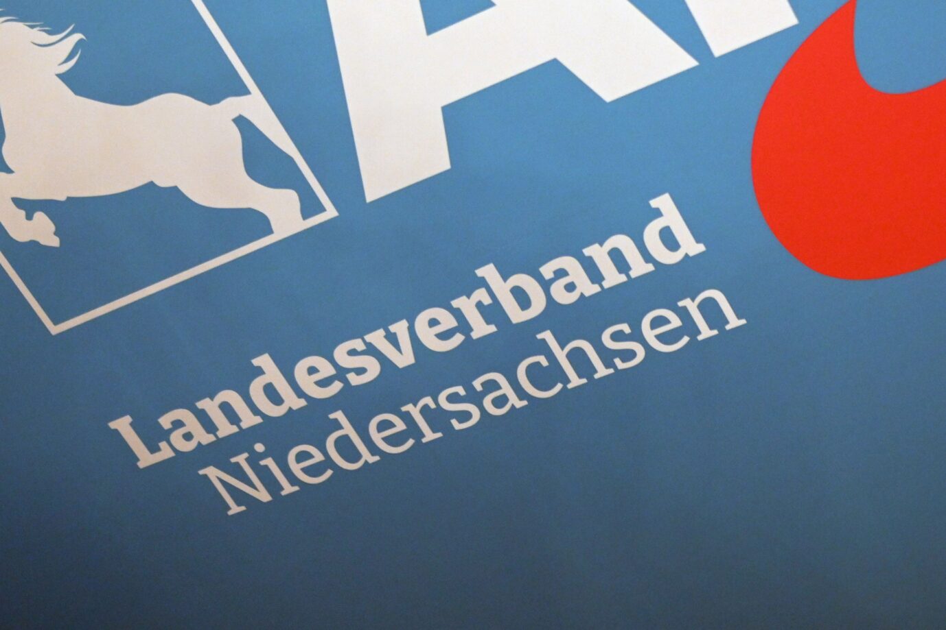 Das Logo des AfD Landesverband Niedersachsen hängt an einer Wand im Saal.
